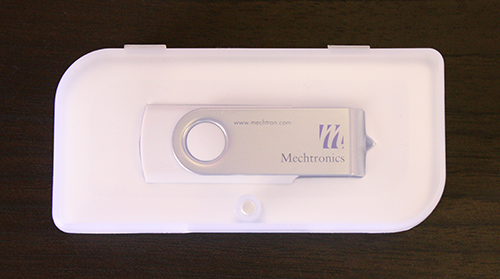 A White SWM Style Custom USB Drive Inside A Closed Clear Plastic Case