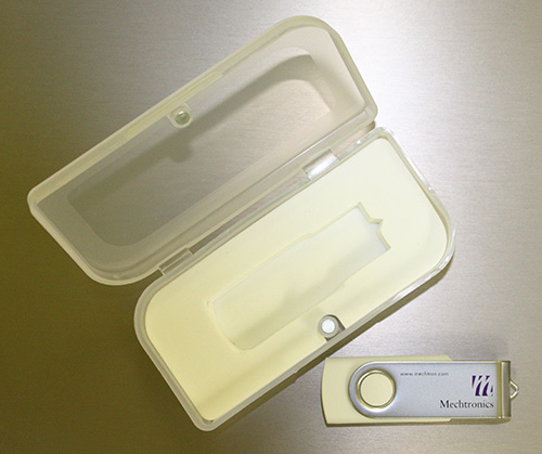 A White SWM Style Custom USB Drive Next To An Open Clear Plastic Case